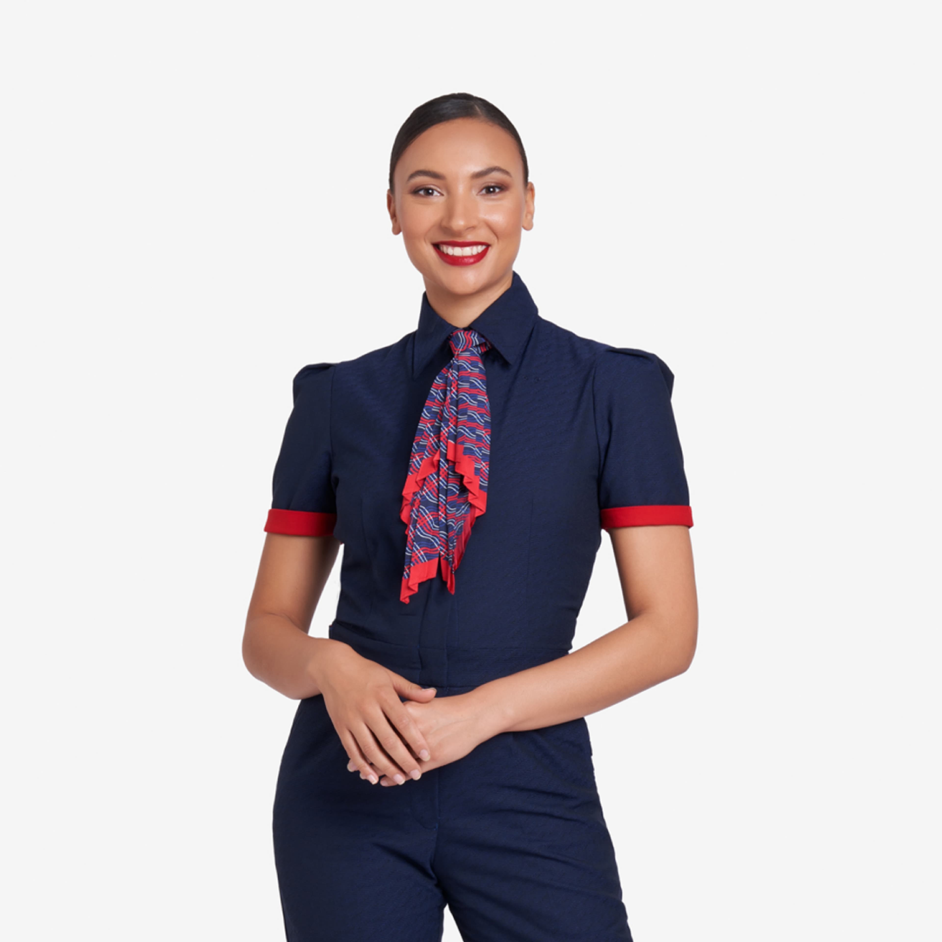 "Flight attendant wearing a navy blue uniform with red cuff accents and a patterned red and blue neck scarf, smiling against a plain white background."