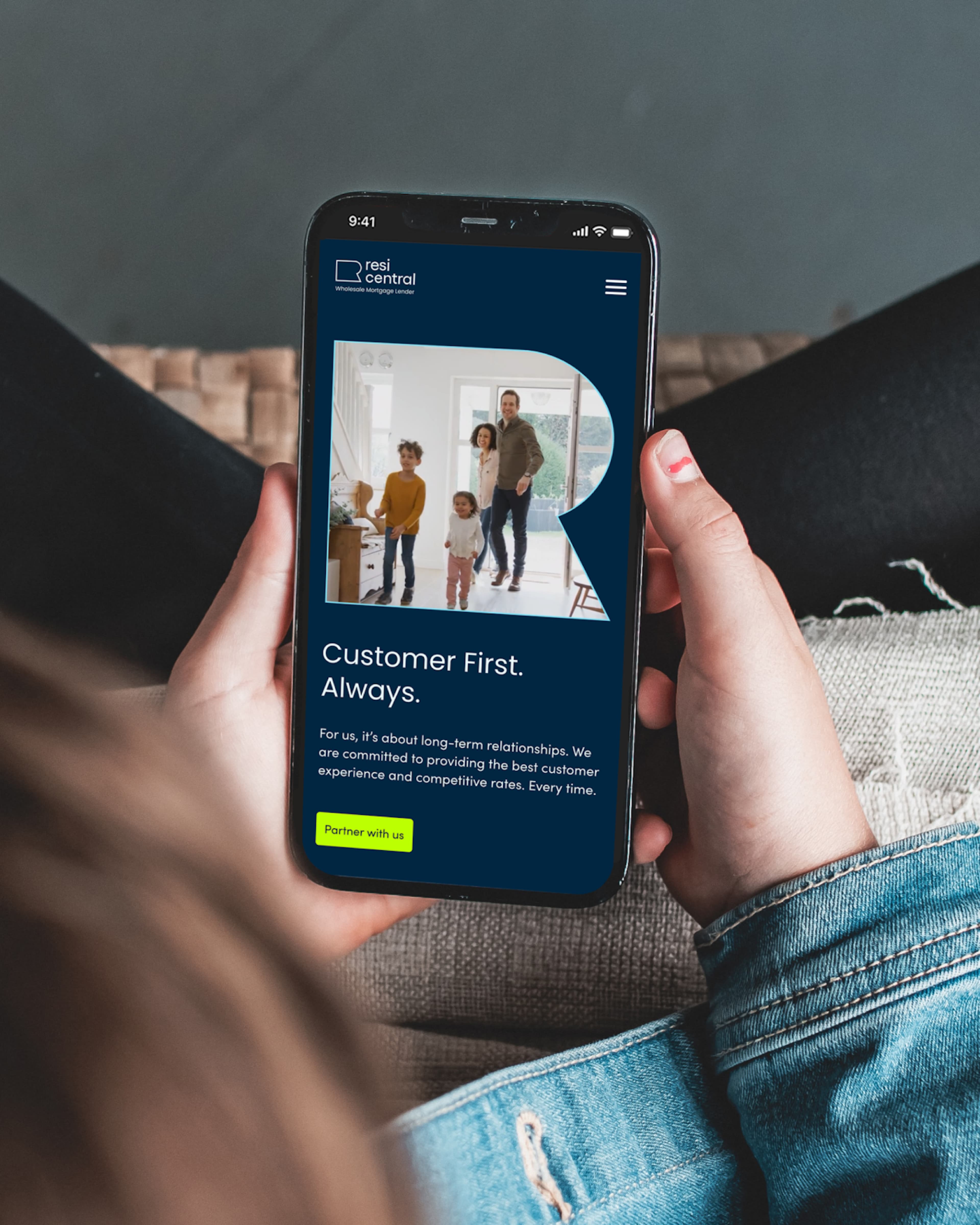 Person holding a smartphone showing the Resi Central Wholesale Mortgage Lender website, featuring a family photo and the tagline "Customer First. Always." on a dark blue background.