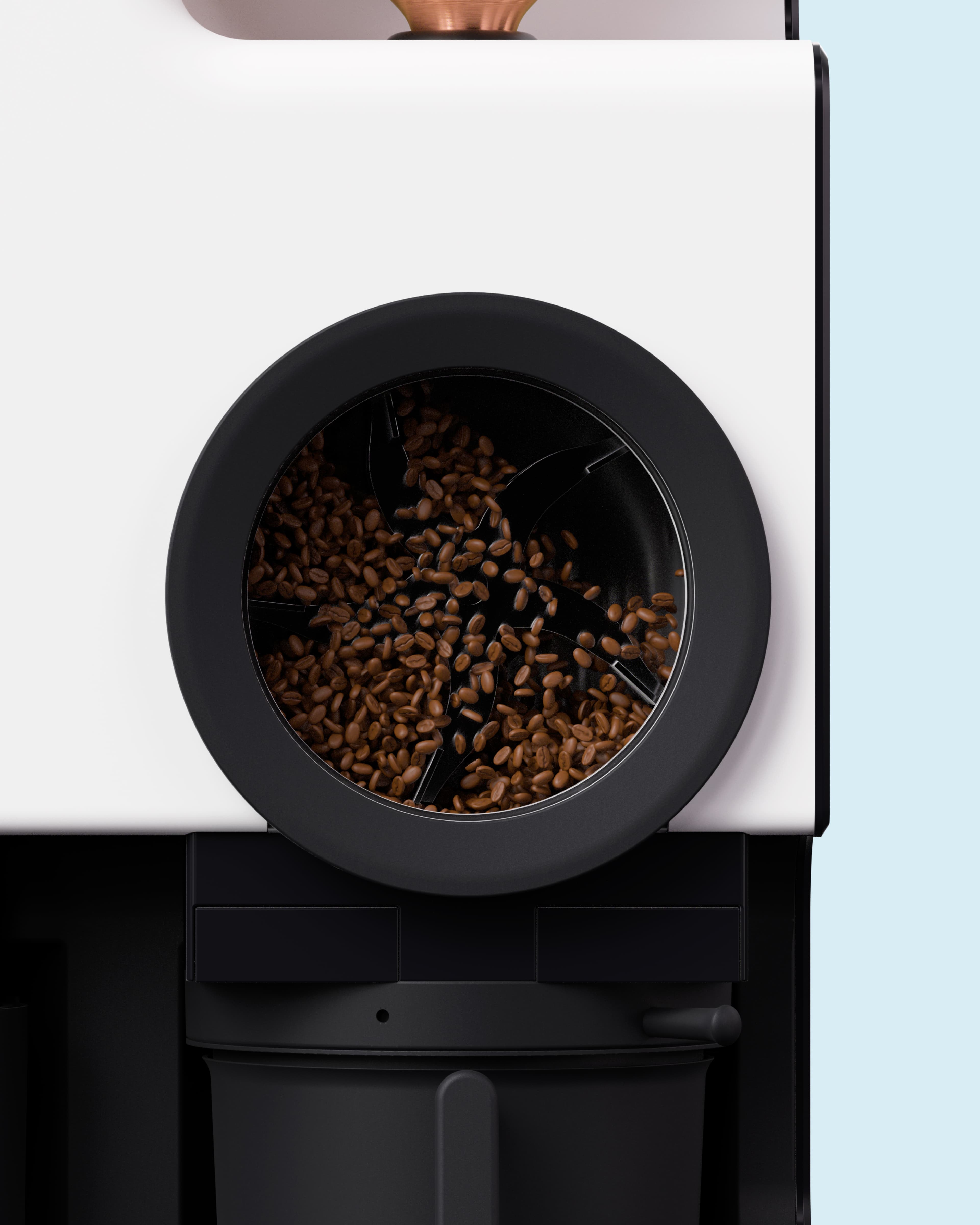 Close-up of coffee beans inside the circular viewing window of a Bellwether commercial coffee roaster, with a white and black exterior against a light blue background.
