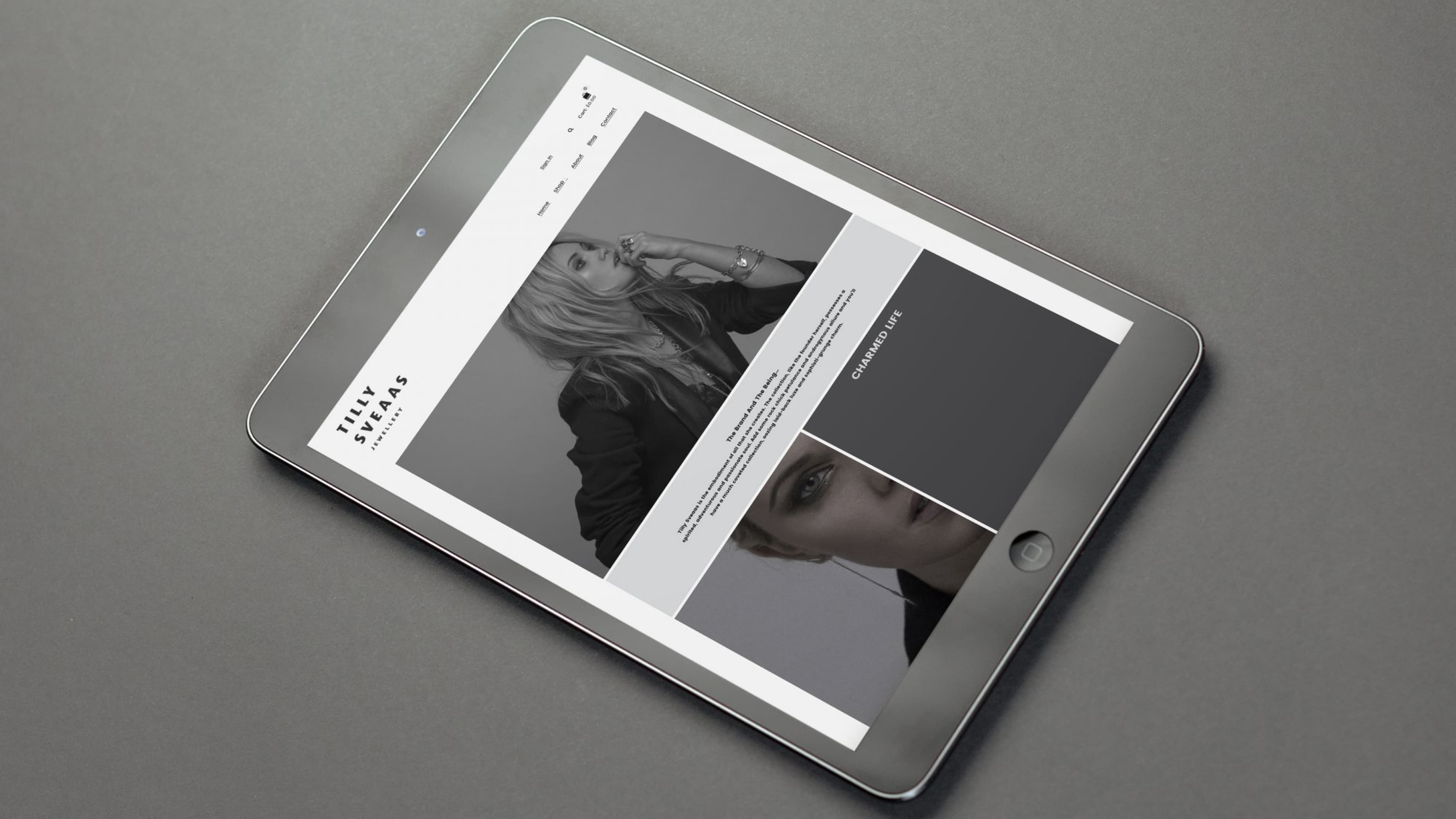 Tablet displaying the Tilly Sveaas Jewellery website, showing a black and white editorial layout with a model wearing jewellery and a "Charmed Life" blog section.