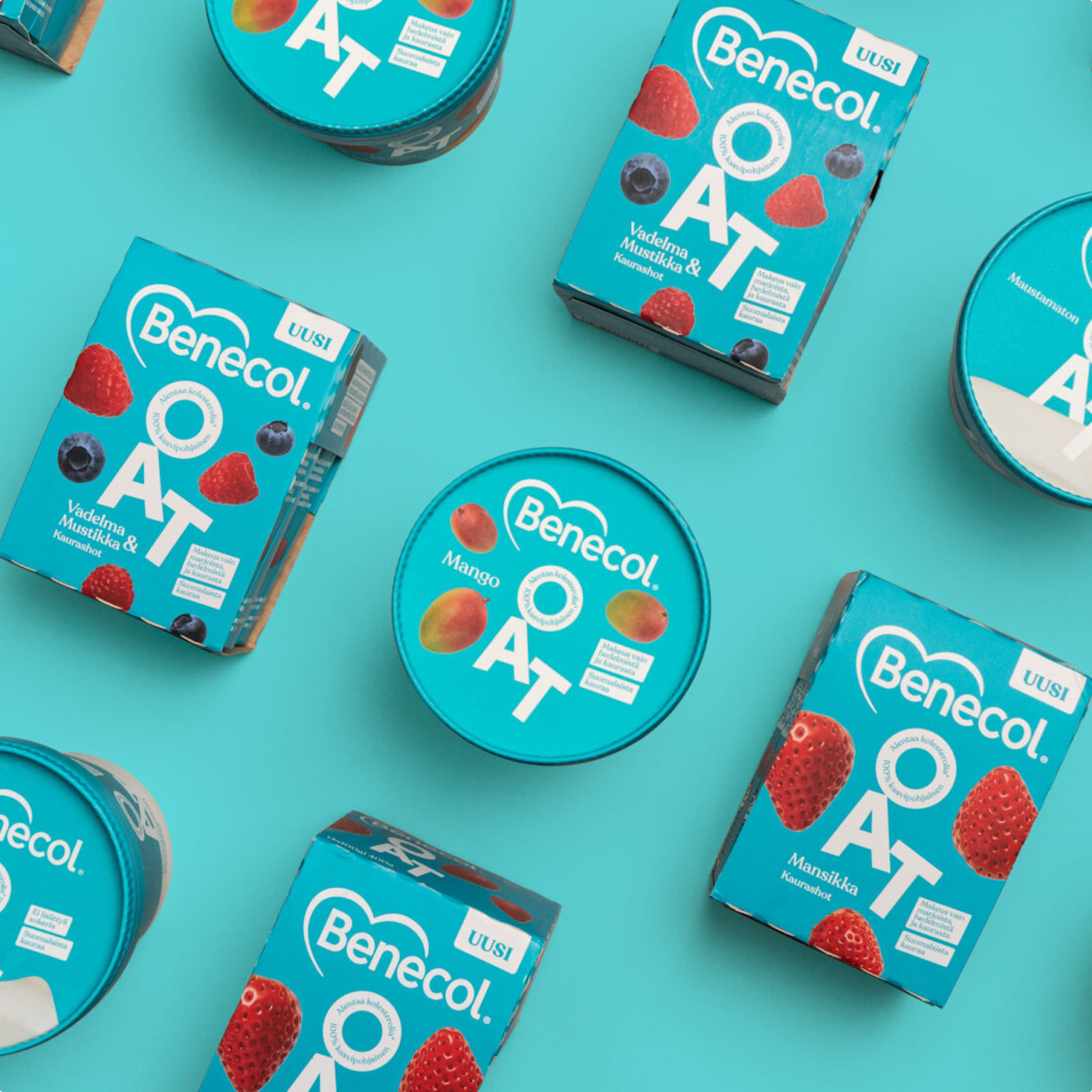 Benecol OAT plant-based shot products in teal packaging, showing three flavour varieties: Raspberry & Blueberry (Vadelma Mustikka), Strawberry (Mansikka), and Mango, arranged on a turquoise background.