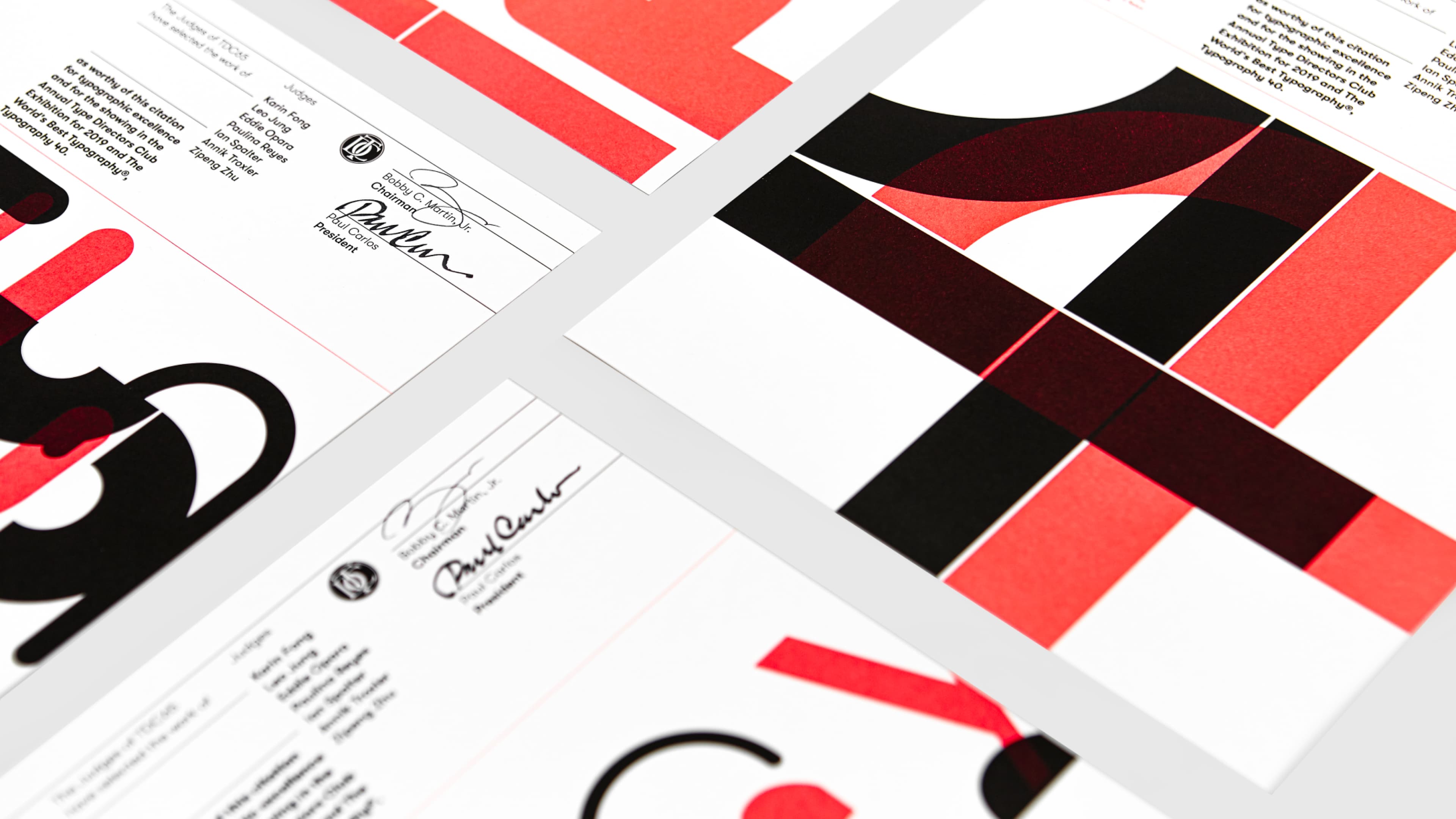 Type Directors Club award certificates featuring bold red and black typographic design, with signatures from Chairman Bobby C. Martin Jr. and President Paul Carlos, shown in two overlapping prints.