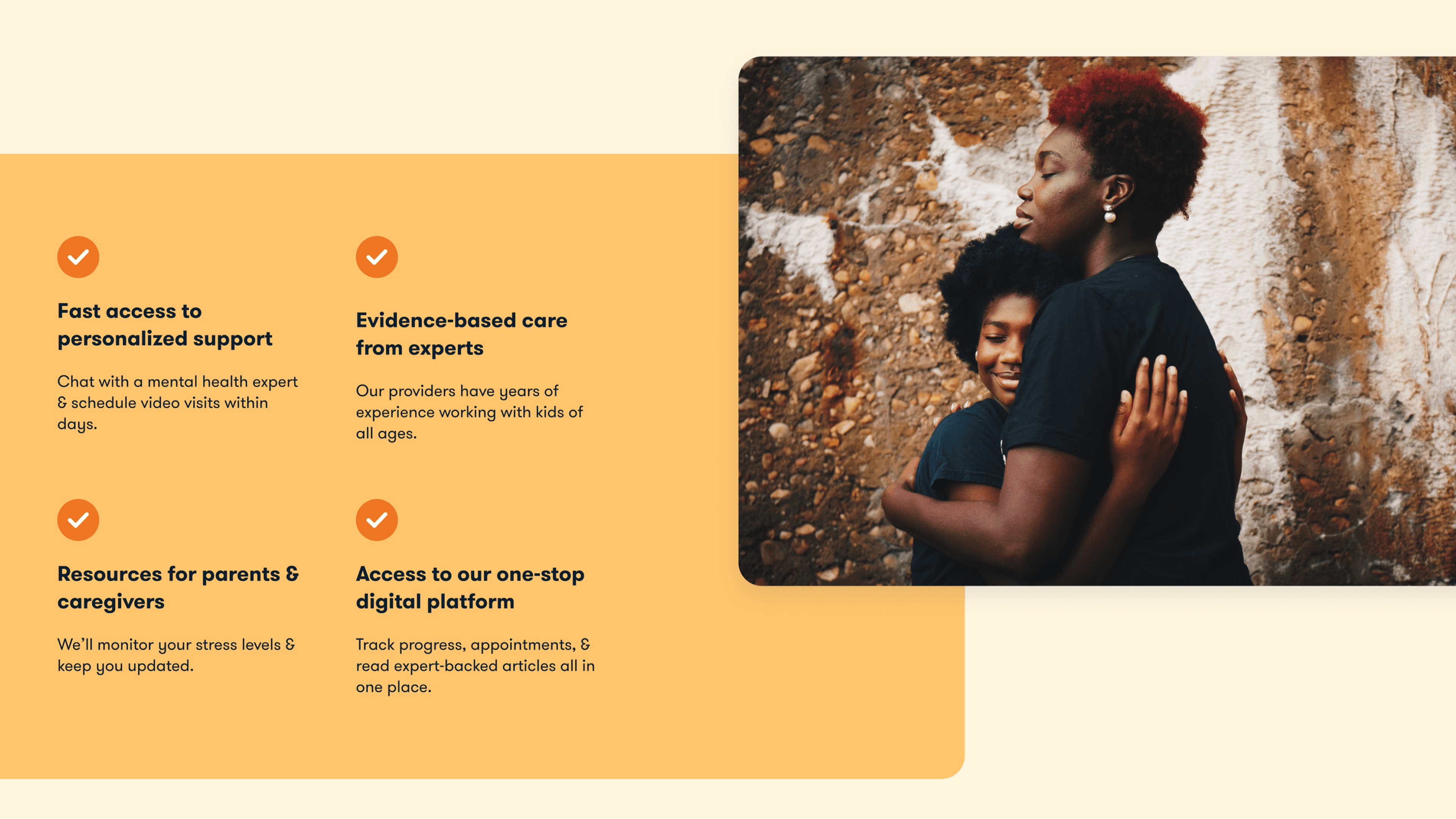 A mother with red natural hair hugging her child against a stone wall, both with eyes closed in a warm embrace.