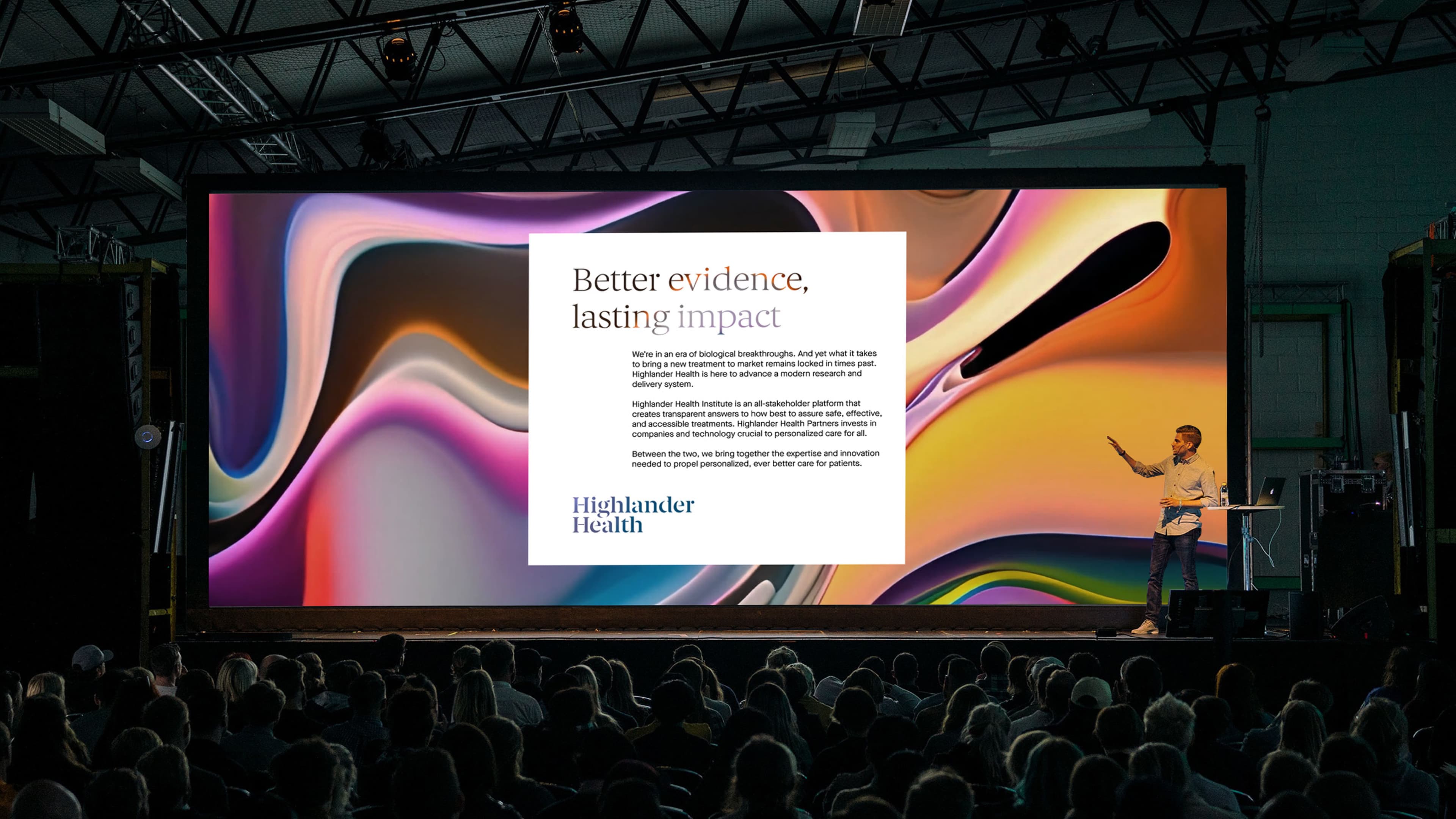A presenter on stage at a conference gestures toward a large screen displaying a Highlander Health slide titled "Better evidence, lasting impact," describing their mission to advance modern healthcare research and delivery.