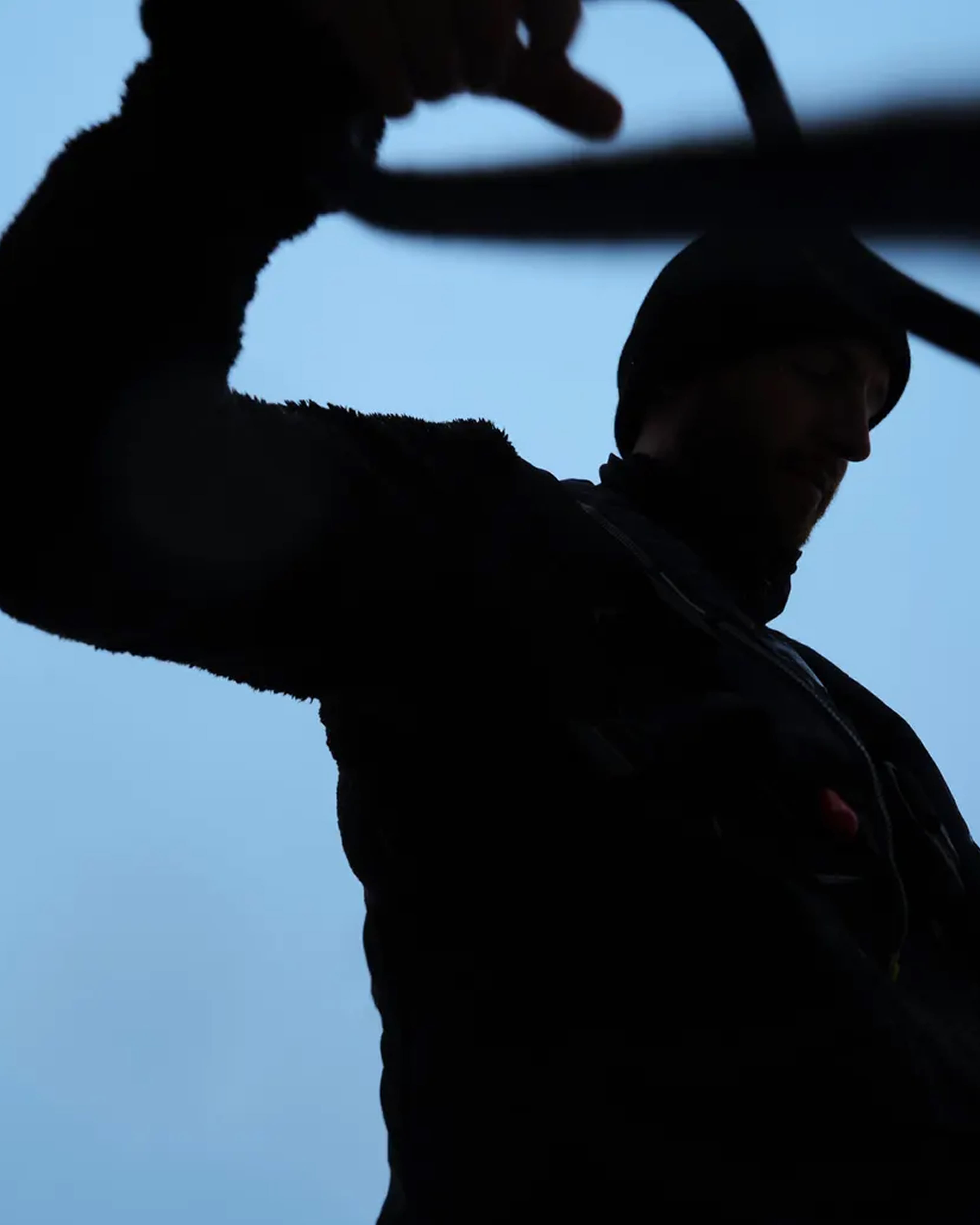 A silhouette of a man working on an engine with a blue background and black detail.