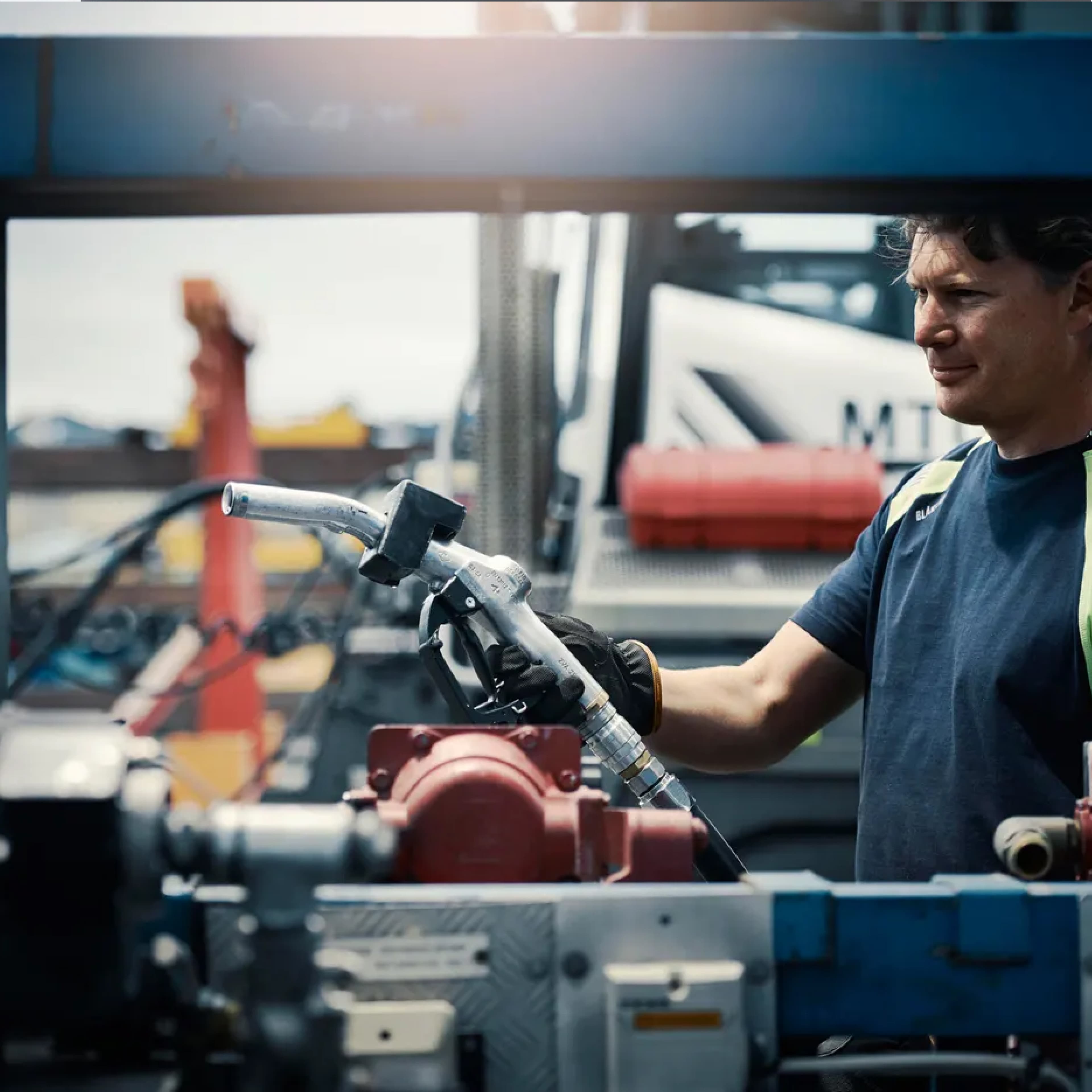 Picture of a man working on an engine outside with sun shining from the back.